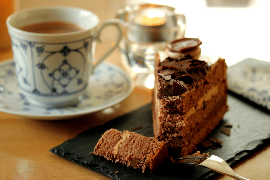 A cup of tea, and cake served in plate.