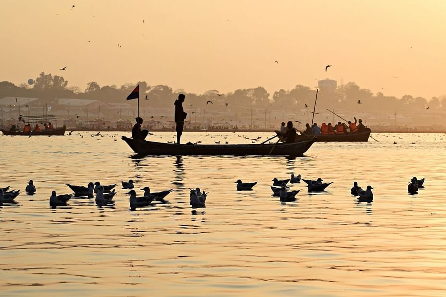 alt-text Silhouettes of people on boat in water and the ducks.