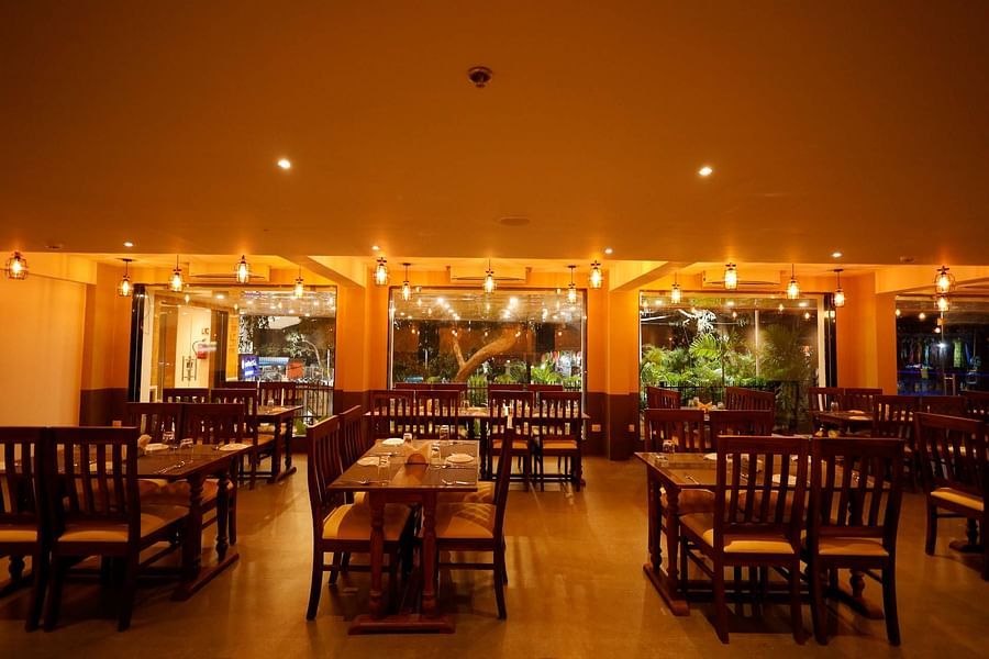 Dining area with chairs and tables and lights on the ceiling at Vagator Downtown, Goa