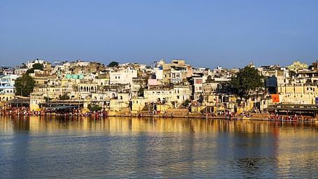 Buildings line the shore of a body of water under a clear sky.