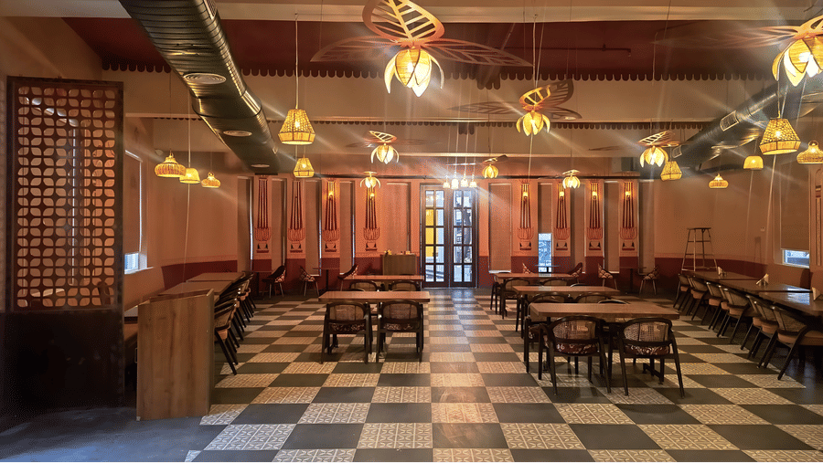 Overview of a warm, dimly lit restaurant interior featuring several tables covered in red tablecloths and a black and white checkered floor at Kadamb Kuteer, Vrindavan.