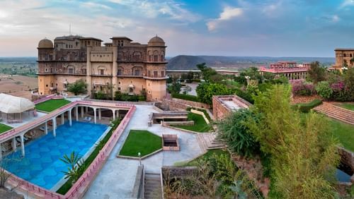 Facade view of  Tijara Fort-Palace - 19th Century, Alwar with a swimming pool in the foreground.