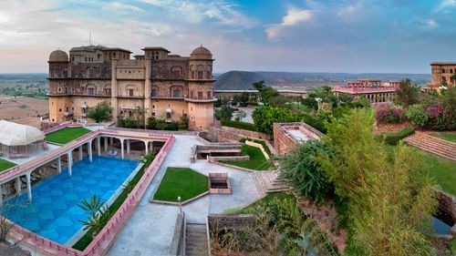Facade view of  Tijara Fort-Palace - 19th Century, Alwar with a swimming pool in the foreground.