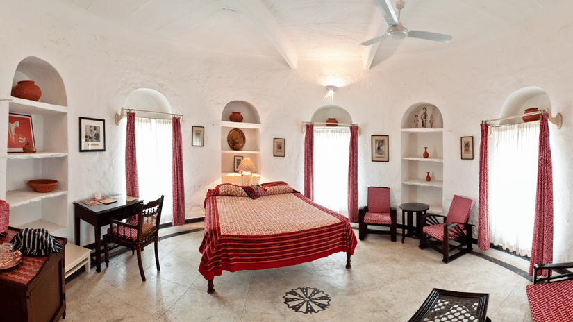 interior view of the Mubarak Mahal - Countryside View room with a queen size bed, a ceiling fan, several chairs and paintings on the wall