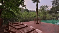 A poolside area features lounge chairs and trees, offering a relaxing outdoor space. - Abad Brookside Lakkidi, Wayanad