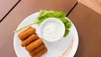 Plate of fried food sticks with a white dip and green garnish. - Abad Brookside Lakkidi, Wayanad