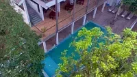 An aerial view shows a pool surrounded by trees and a building, highlighting the property's layout. - Abad Brookside Lakkidi, Wayanad