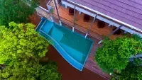 An aerial view shows a pool and a building with a purple roof, showcasing the property from above. - Abad Brookside Lakkidi, Wayanad