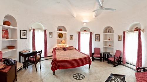 interior view of the Mubarak Mahal - Countryside View room with a queen size bed, a ceiling fan, several chairs and paintings on the wall