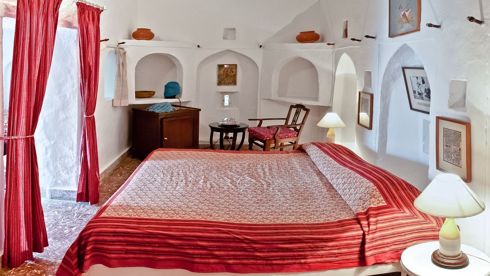 Hill Fort Kesroli 14th Century Alwar - interior view of the Bhawani Mahal - Fort View with a king seize bed and red curtains