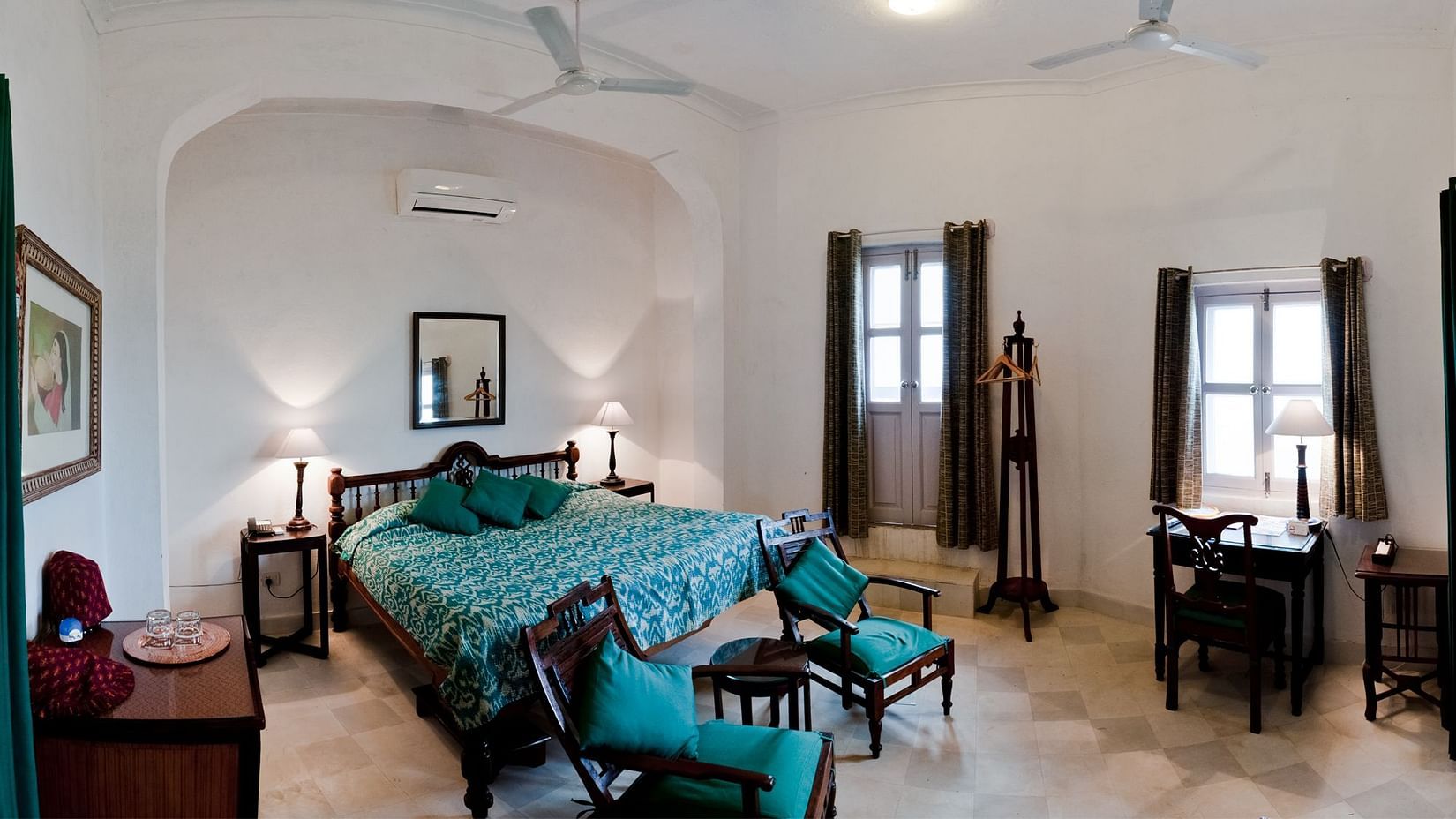 interior view of the Koel Mahal - Countryside View room with a king size bed draped in a teal bed cover
