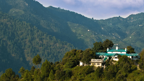 Aerial view of The Ramgarh Bungalows 19th Century Hotel, overlooking forested mountains and valleys in Nainital.