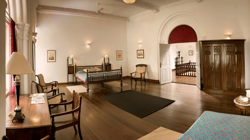 The Tower House - full view of The Mateu Suite with striking wooden interior and three couches with a single bed in the corner of the room