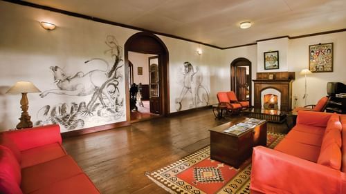 A living room showcasing red coloured sofas and a coffee table with drawings on the wall - Wallwood Garden - 19th Century, Coonoor