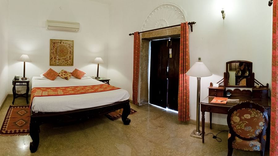 Deo Bagh - 17th Century, Gwalior - a king size bed and a work desk at the Dhanur Mahal - Naubagh / Garden View room in Gwalior