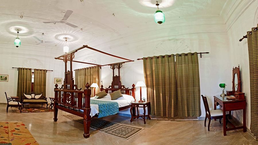 Deo Bagh - 17th Century, Gwalior - a king size bed and a work desk in the corner at Sakhya Raja Mahal - Naubagh / Garden View