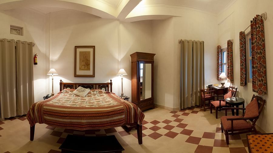 Hill Fort Kesroli 14th Century Alwar - interior view of the Maan Burj room with king size bed, chairs, and lamps on either sides of the bed