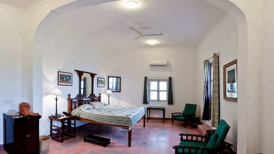 interior view of the Rajhans Mahal - Countryside View with a king size bed, a ceiling fan,  wooden chairs and an archway