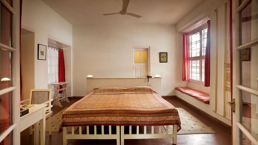 The Tower House - The Cunes Room with two single beds joined together and a large window with red couch in front