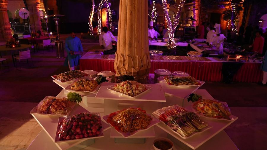 A buffet spread with various dishes on white square plates is arranged on a table with a central pillar at Tijara Fort-Palace - 19th Century, Alwar. 