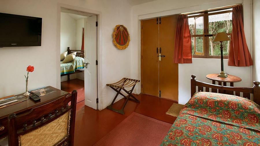 A single bed, small window, a study table and chair inside Red Cedar room - Wallwood Garden - 19th Century, Coonoor
