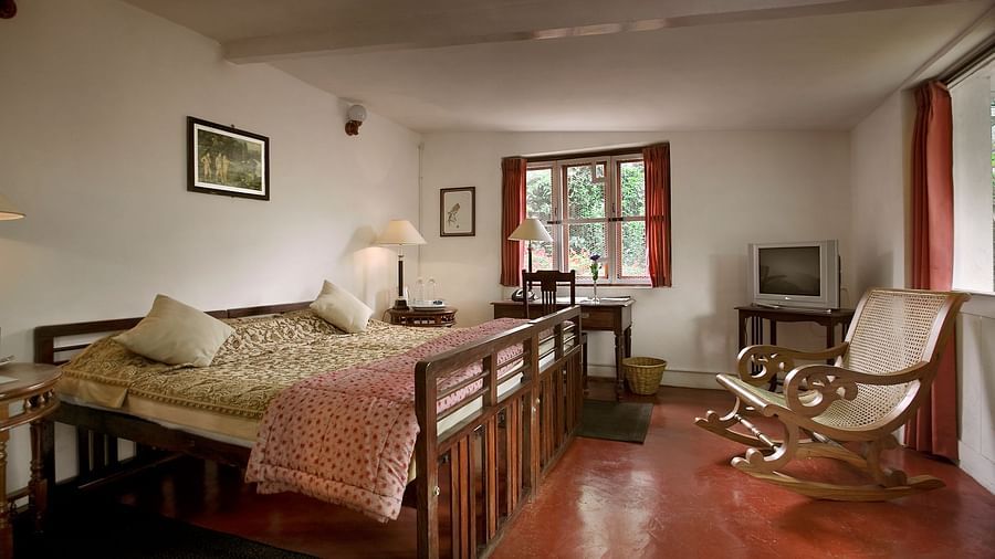 Two single beds made into a double bed with a rocking chair next to it inside Pine room - Wallwood Garden - 19th Century, Coonoor