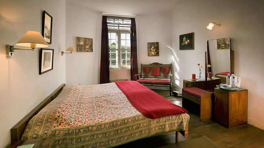 A double bed with a makeup table, mirror and chair opposite to the bed and a sofa on the side inside Laburnum room - Wallwood Garden - 19th Century, Coonoor