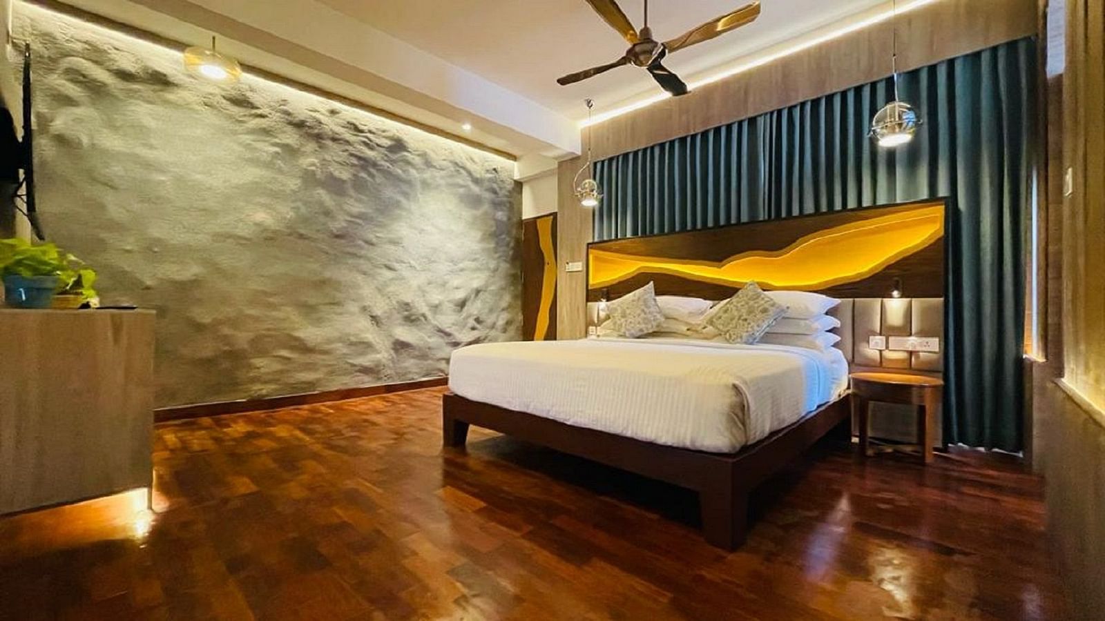 An image of timber Lodge room with a king size bed, ceiling fan, decorative items, and wall paintings - GReaT trails Kodaikanal by GRT Hotels