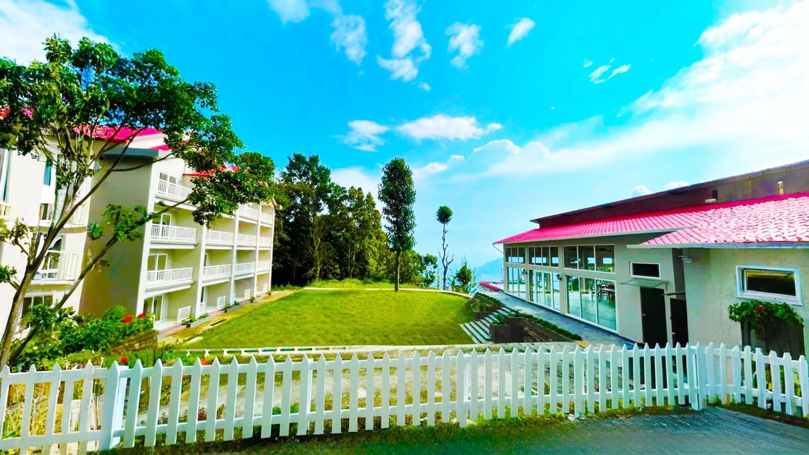 Scenic exterior of Yashshree Kalimpong, a charming hotel nestled amid lush greenery, offering a peaceful stay with a bright and inviting atmosphere.