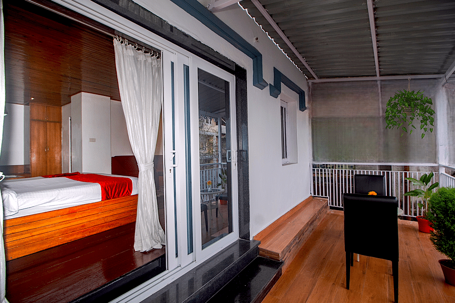 Outdoor balcony with wooden railings, potted plants, and a view of the surroundings.