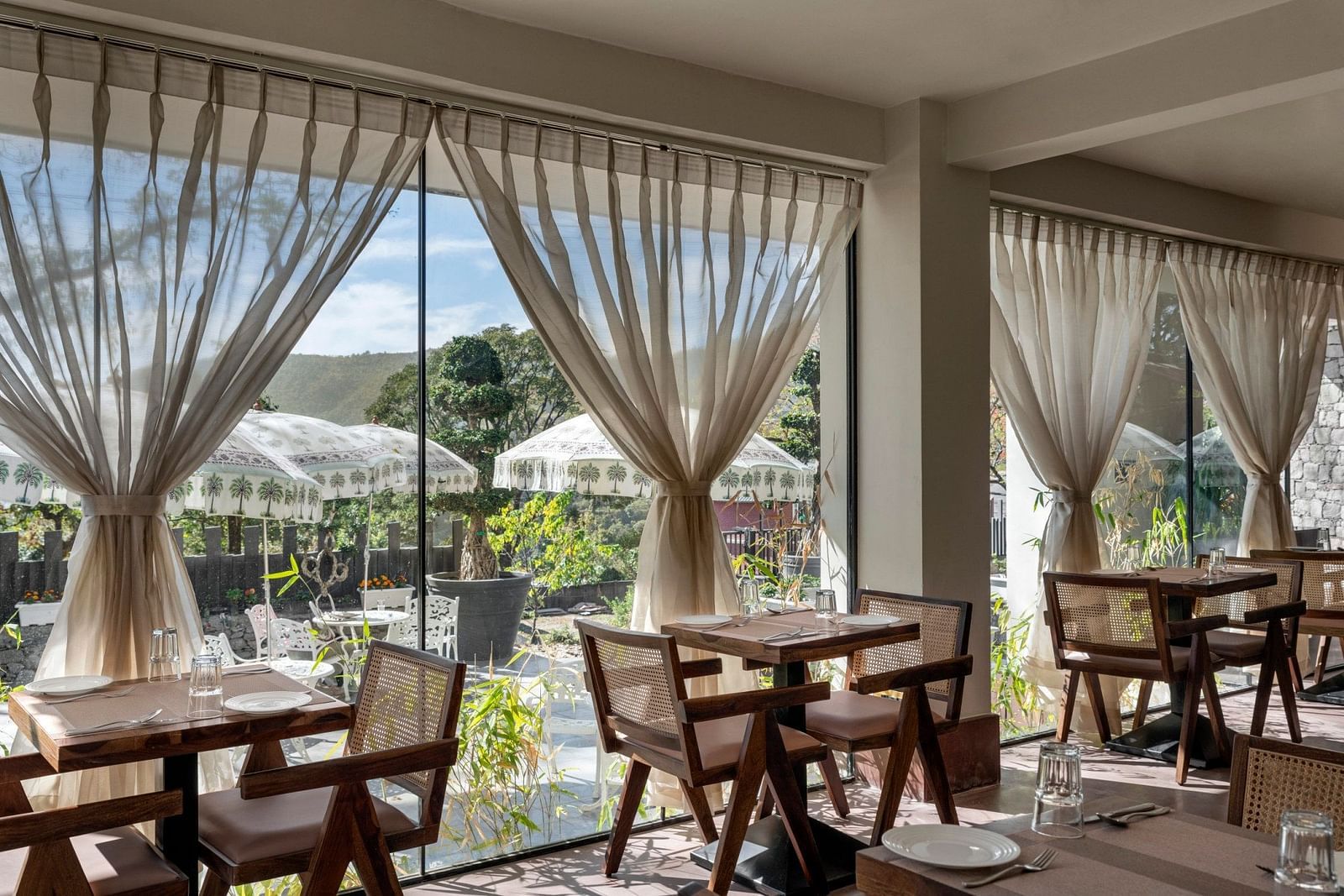 An inside view of a restaurant with chairs placed beside a glass window - The Samai, Bhimtal