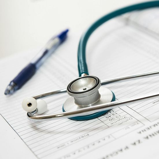 A teal stethoscope and a blue pen rest on top of a patient's medical chart.
