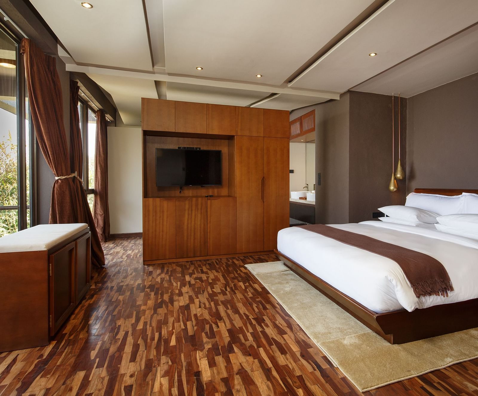 Modern bedroom with a large bed, wooden flooring, and contemporary furnishings.