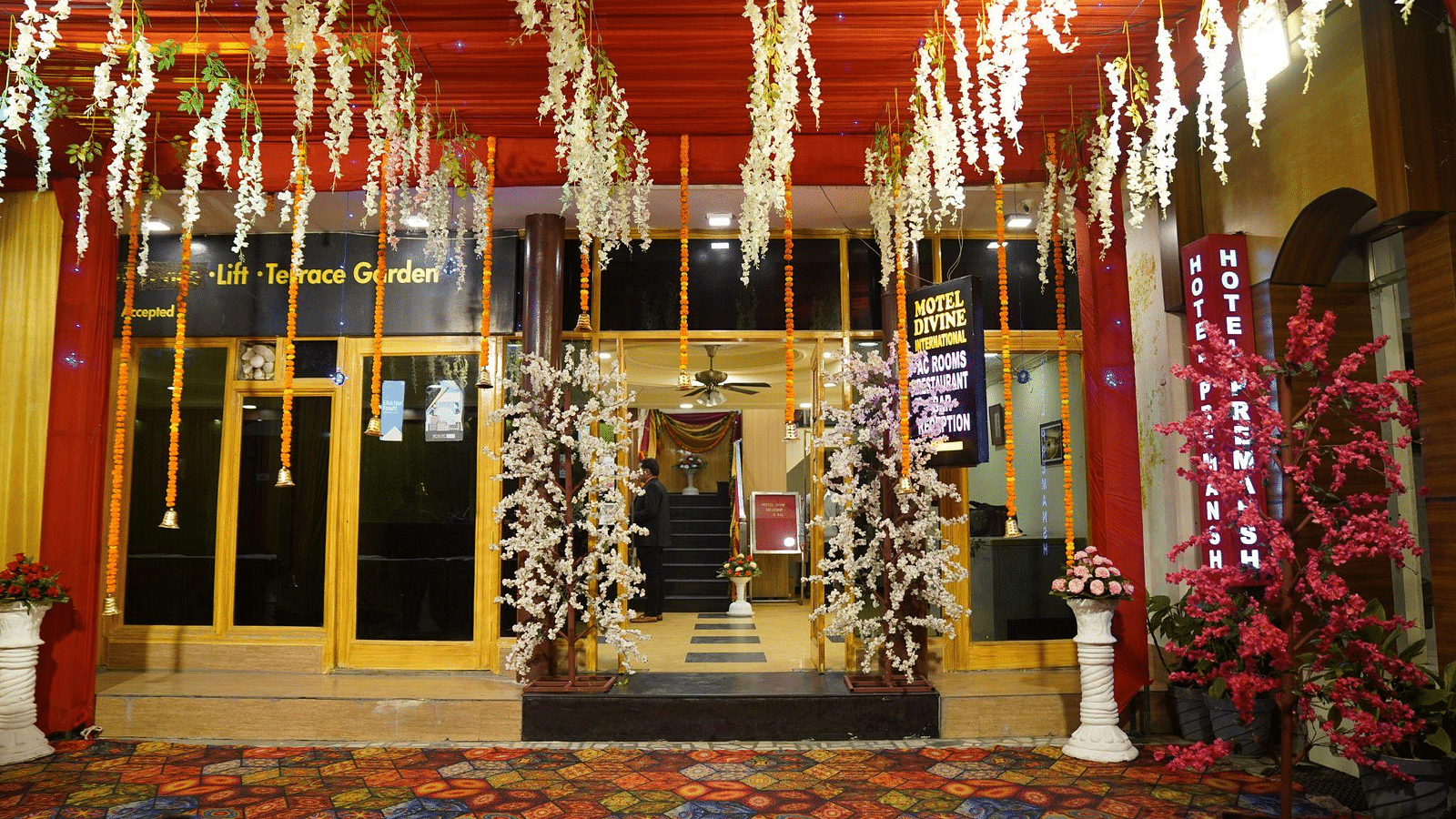 An image of a hotel entrance in Roorkee, featuring hanging flowers that enhance its welcoming atmosphere - Motel Divine International, Roorkee