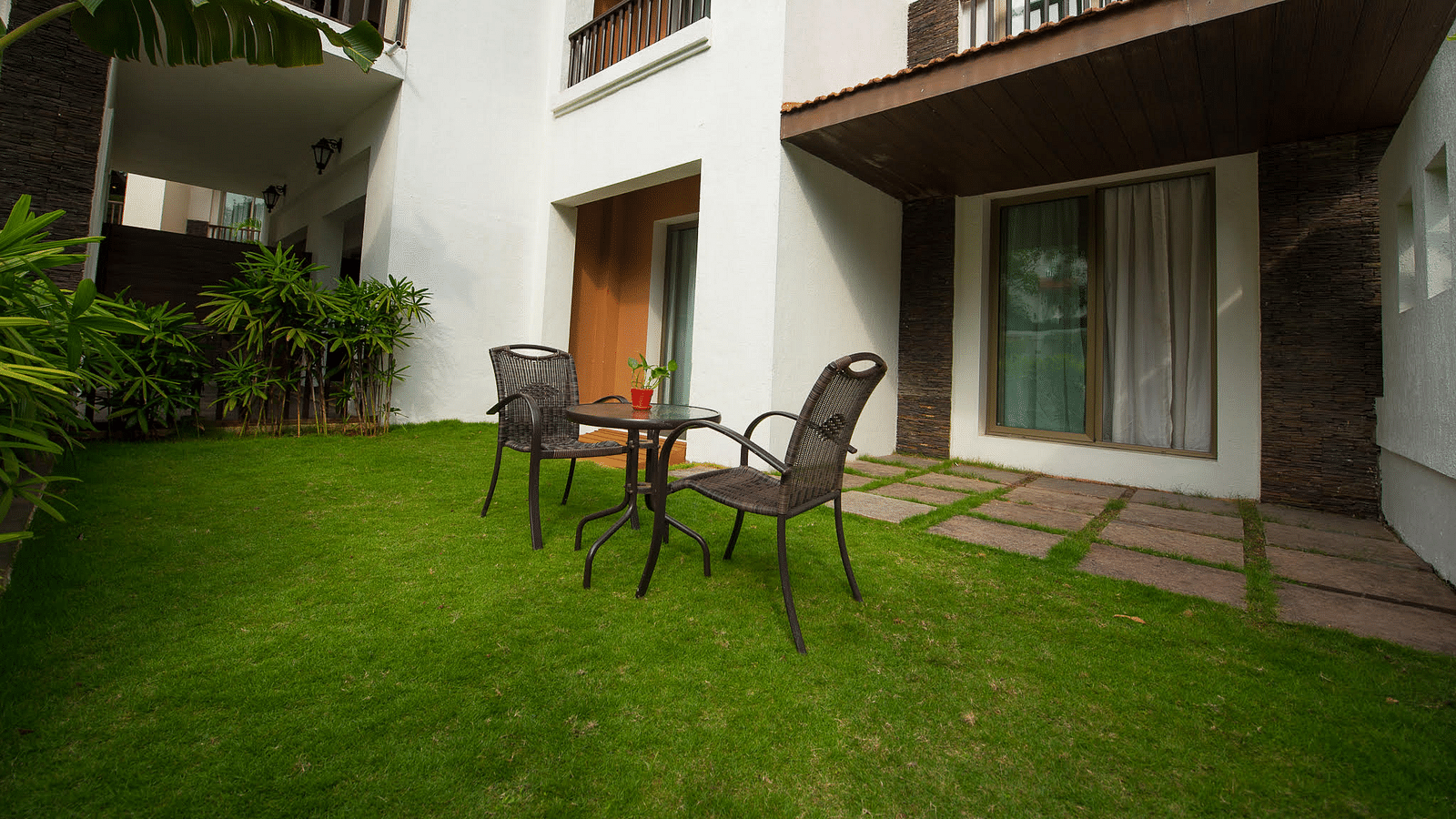 A table and two chairs set up on a lawn next to a suite - Rhythm Lonavala.