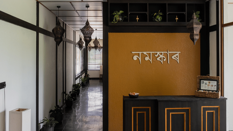 The reception area featuring a mustard-yellow wall with Namaskar written in Assamese script at Rhino & River Wildlife Retreat & Spa, Pobitora.