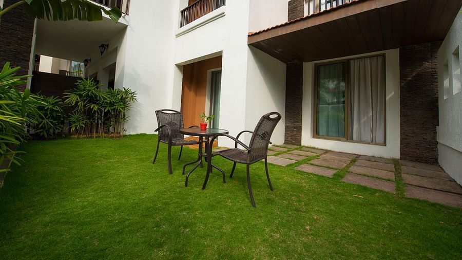 A table and two chairs set up on a lawn next to a suite - Rhythm Lonavala.