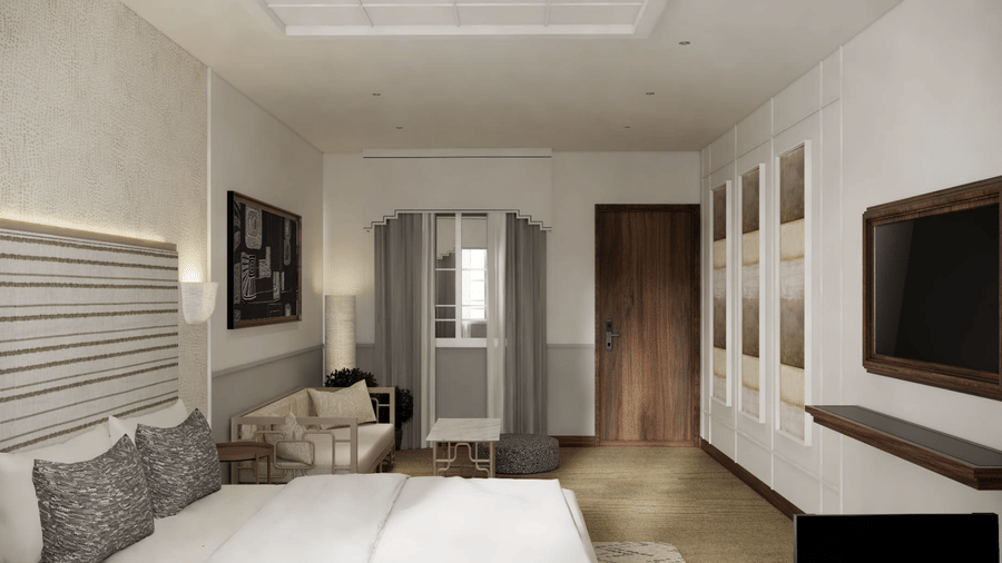 A bedroom with a wooden door, a wall-mounted television, and a small seating area with a sofa at Shilton Suites, Bengaluru.