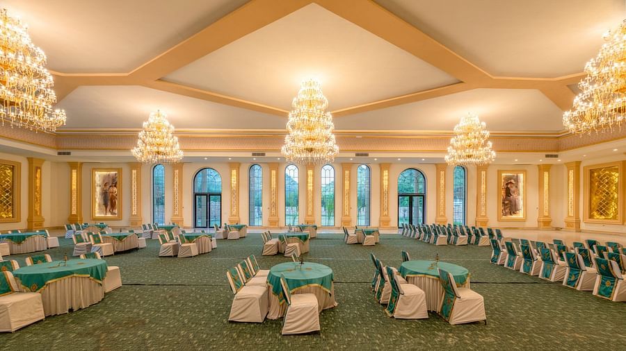 Side view of a banquet hall featuring round tables with chairs and chandeliers elegantly hanging from the ceiling at Valley by Grassfield.