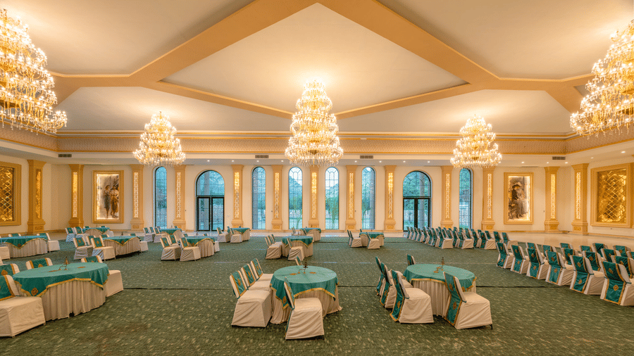 Round tables and crystal chandeliers in The Royal Knot banquet hall at Valley by Grassfield, a destination wedding venue in Jaipur.