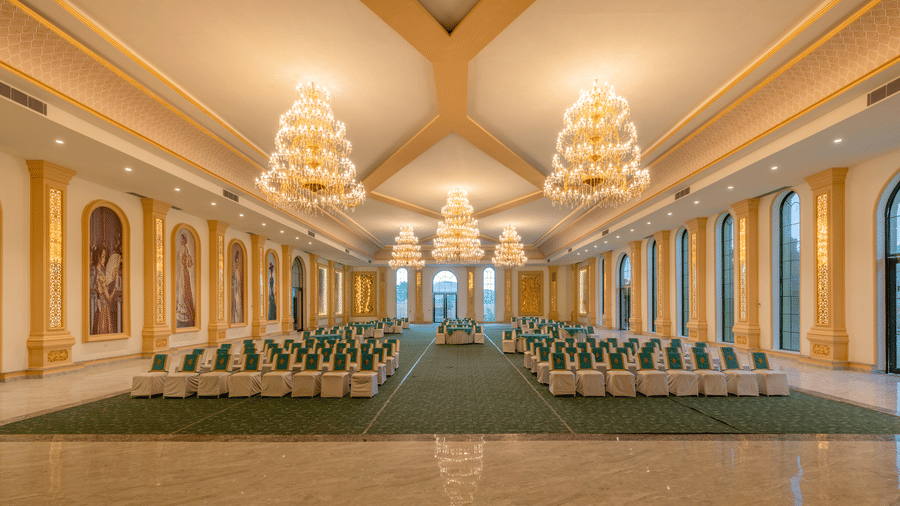 Front view of The Royal Knot banquet hall with chandeliers and banquet seating at Valley by Grassfield, a wedding venue in Jaipur.
