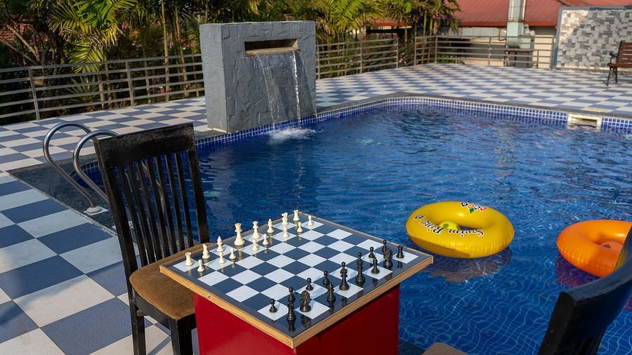 A swimming pool area with a chessboard and outdoor furniture, including inflatable rings in the pool | Woodstock Resorts, Coorg