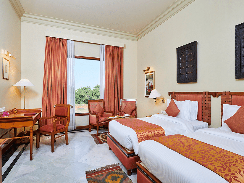 a deluxe room at The Ummed Jodhpur, Palace Resort and Spa with twin bed featuring soft white linens and a window offering great view