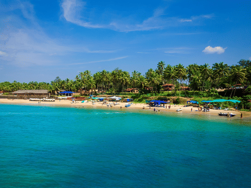 An aerial view of people basking in the sun near the blue water of the Colva Beach. It is one of the best tourist attractions in South Goa.