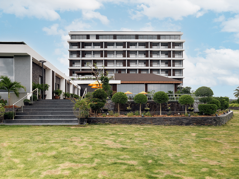 The exterior façade of Cloud9 Sarovar Premiere, Palolem Goa, framed by lush greenery and a cloudy sky, creates a peaceful and inviting atmosphere, making it one of the top hotels near Palolem Beach, South Goa.