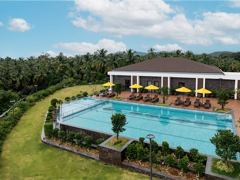 An overhead view of the swimming pool, surrounded by lush plants and greenery, at Cloud9 Sarovar Premiere, Palolem Goa, creates a tranquil, tropical atmosphere