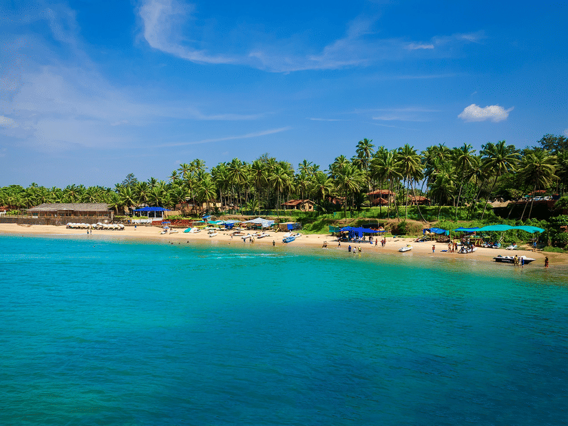 An aerial view of people basking in the sun near the blue water of the Colva Beach. It is one of the best tourist attractions in South Goa.