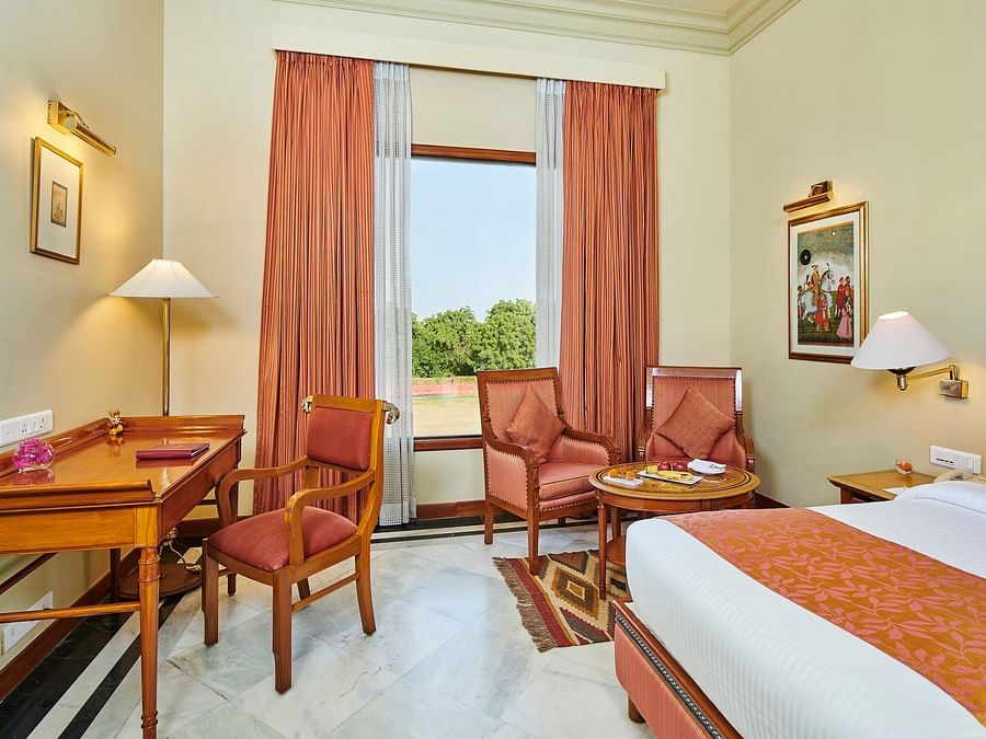a deluxe room at  The Ummed Jodhpur, Palace Resort and Spa with king size bed featuring soft white linens and a window offering great view