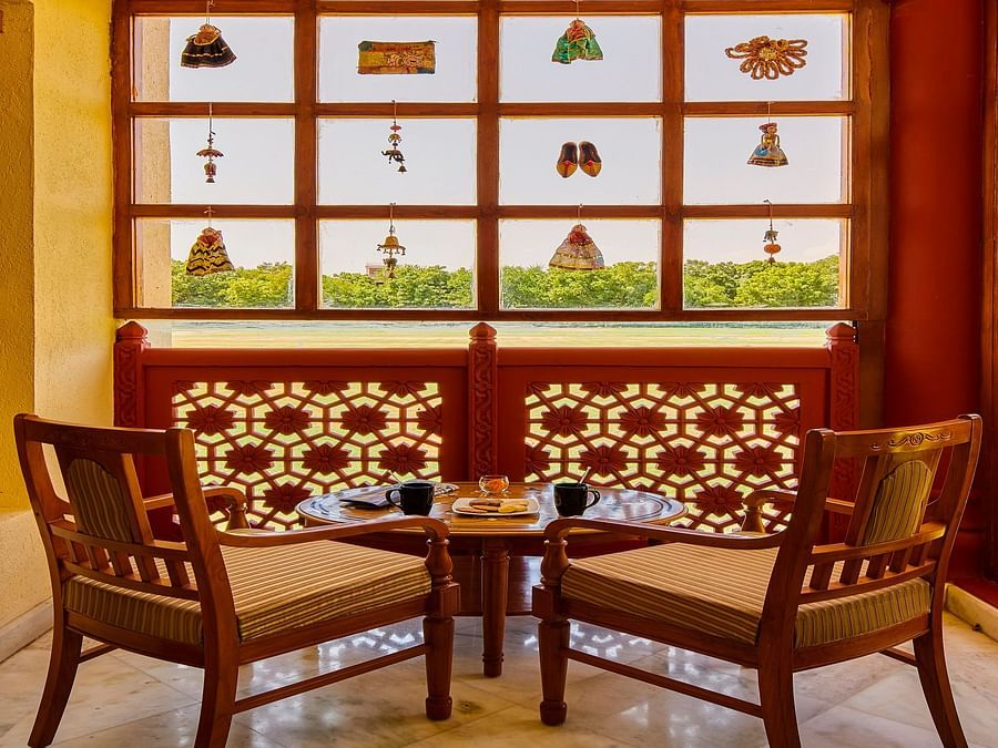 Royal Suite Courtyard with two chairs and a teapoy in front of a beautiful window - The Ummed Jodhpur, Palace Resort and Spa