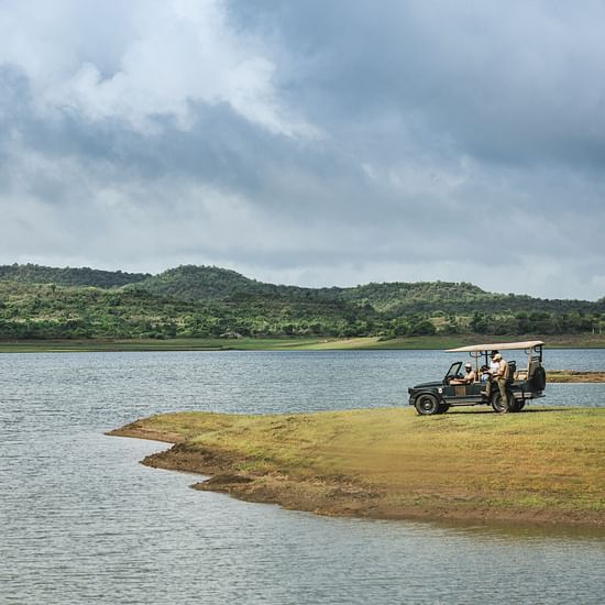 Safari Jeep with Tourists Close by a Lake